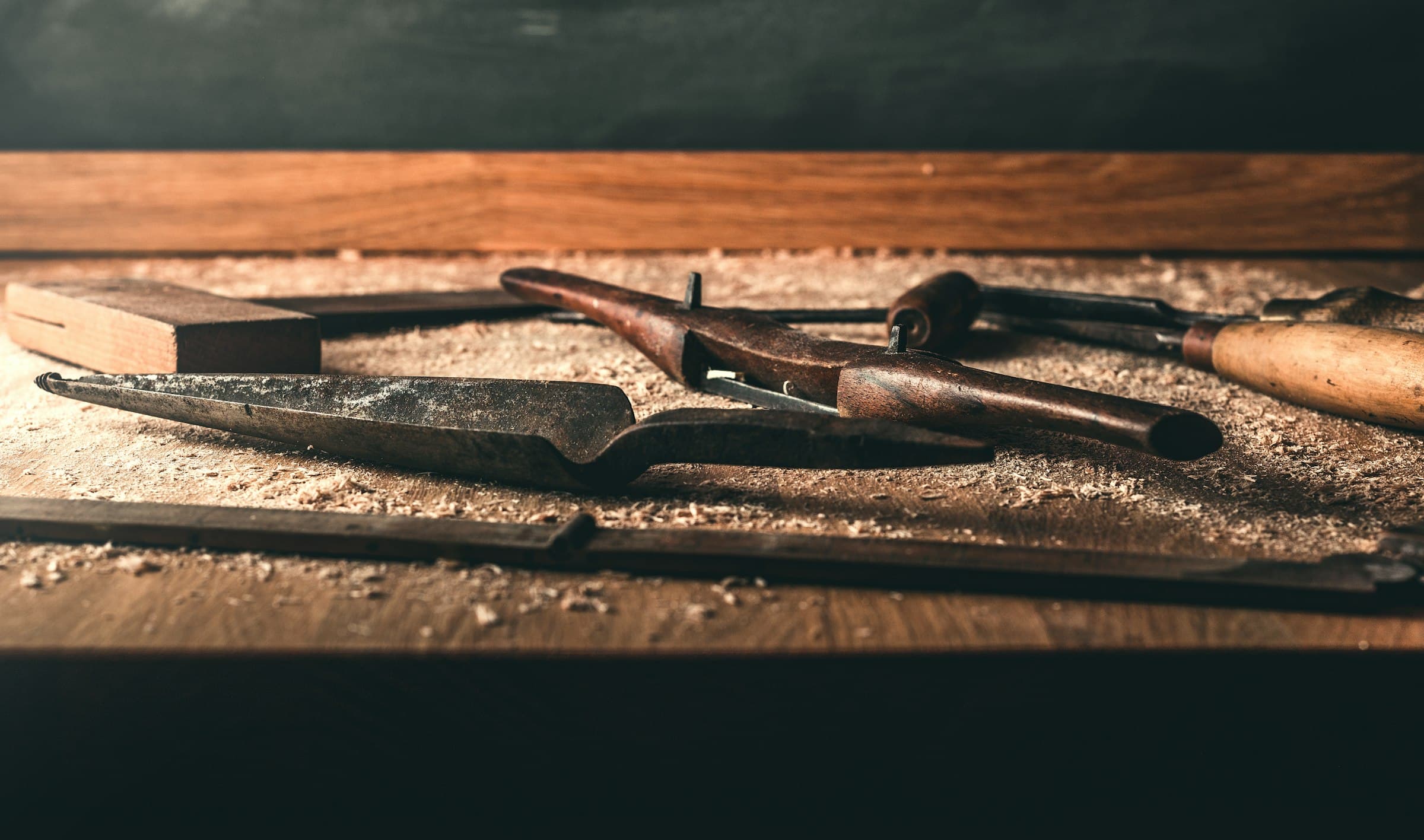 Hand tools and sawdust on a workbench in warm low light